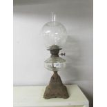 A Victorian oil lamp with clear glass font and floral acid etched shade on a cast iron base.