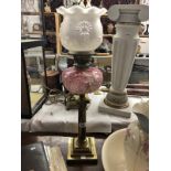 A brass Corinthian column oil lamp with badly damaged pink glass font.