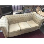 A deep buttoned fabric covered chesterfield sofa.