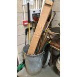 A galvanised dustbin and garden tools.