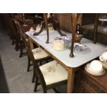 A formica top kitchen table and 2 wheeled back dining chairs.