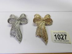 2 jewelled bow brooches, one gold coloured and the other silver coloured.