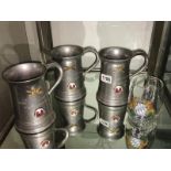 3 Armorial metal tankards and a glass tankard.