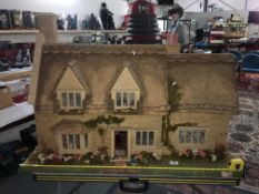 A cottage dolls house designed and made by Mike Marsden along with dolls house furniture etc.