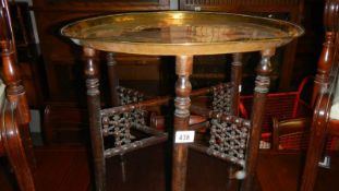 A folding brass topped table.