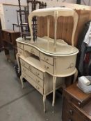 A cream dressing table (no mirror) with a matching chest of drawers and dressing table stool.
