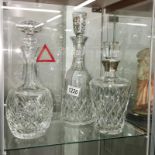 A cut glass decanter with silver collar and 2 others.