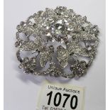 A large circular brooch with 5 butterflies and set with white stones.