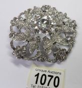 A large circular brooch with 5 butterflies and set with white stones.