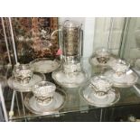 A quantity of glass coffee cups and saucers with white metal decoration.