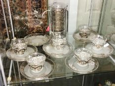 A quantity of glass coffee cups and saucers with white metal decoration.