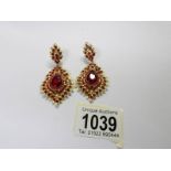 A pair of drop earrings set red stones.