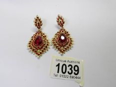 A pair of drop earrings set red stones.