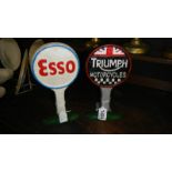 A cast iron Esso sign and a cast iron Triumph sign.