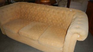 A cream upholstered Chesterfield sofa.