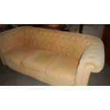 A cream upholstered Chesterfield sofa.