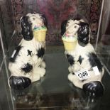 A pair of Staffordshire dogs with baskets in mouths.
