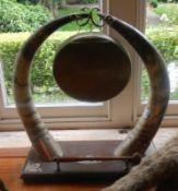 A brass dinner gong supported by tusks.