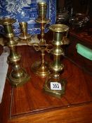 A pair of brass candelsticks and a brass candelabra.