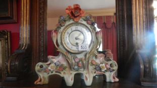 A ceramic mantel clock decorated with flowers.