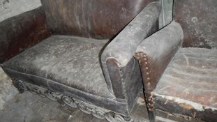 A two seater leather settee with carving on stretchers and an arm chair