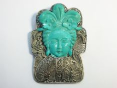 A silver filigree brooch with a carved turquoise depiction of a geisha.