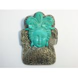 A silver filigree brooch with a carved turquoise depiction of a geisha.