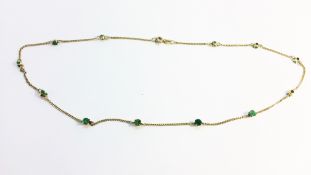 An emerald set chain in 14 carat yellow gold. Set with twelve round facetted emeralds, ETCW 1.2ct.