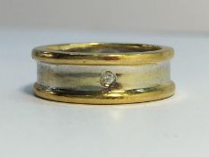 A 9ct white and yellow gold contemporary band ring set with a single diamond.