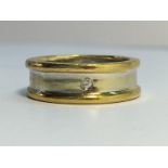 A 9ct white and yellow gold contemporary band ring set with a single diamond.