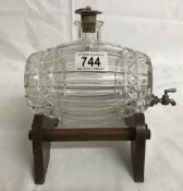 A glass brandy barrel on oak stand.