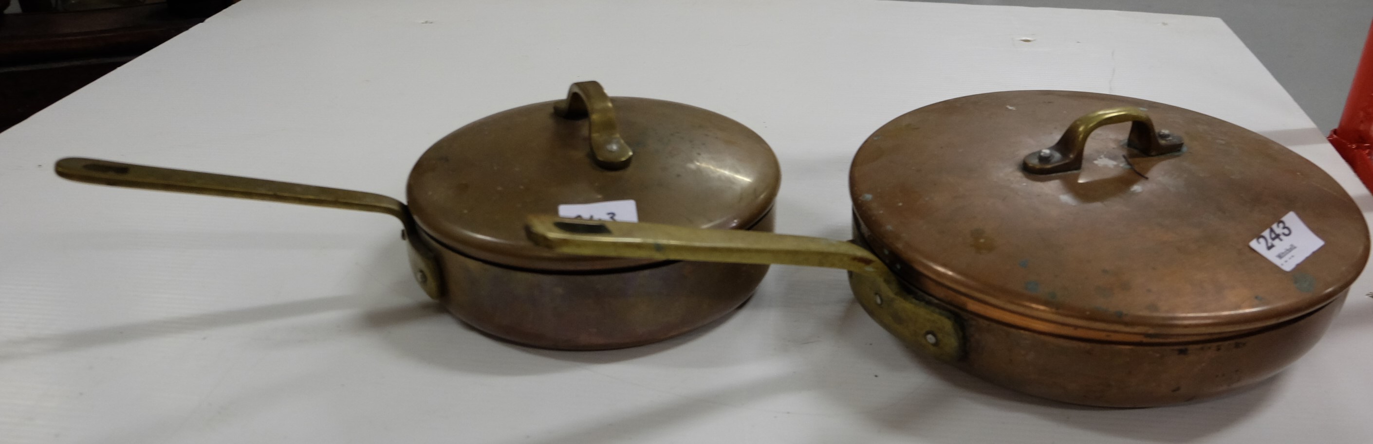 2 circular copper saucepans with lids