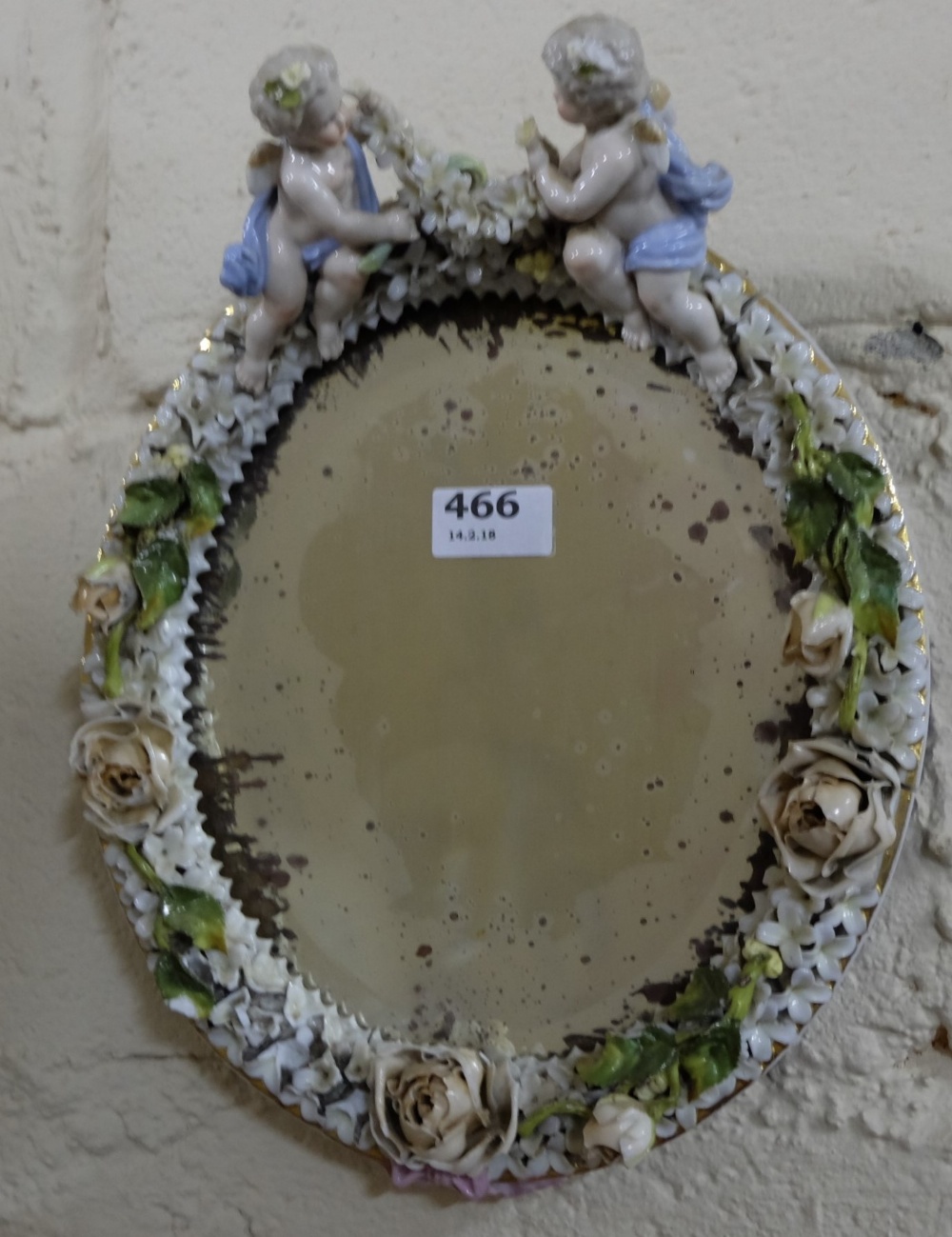19thC Dresden Wall Mirror, the oval shaped insert mounted with applied flowers and two cherub