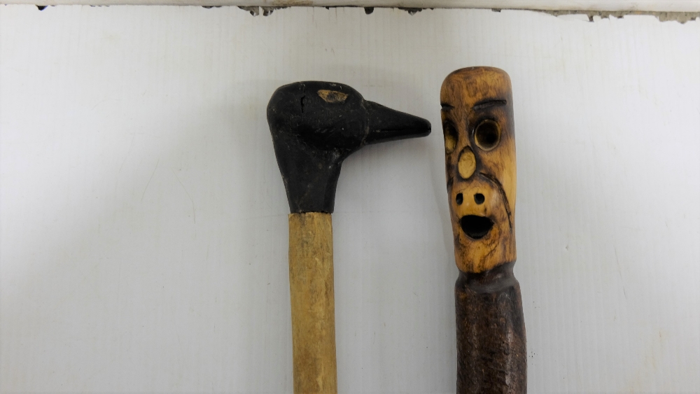 2 wooden walking sticks – 1 mounted with a carved ducks head & 1 with figure of a “spook”, on a - Image 2 of 2