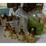 Box of “Bells” whiskey advertising bottles & 2 large glass wine distilling bottles (1 cracked)