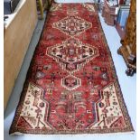 Washed red ground Persian Runner with a traditional medallion design, 2.90m x 0.86m