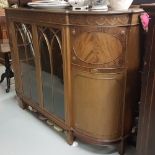 Bowfront Walnut Side Cabinet, decorated with swirls above two glazed doors, enclosing shelves, on
