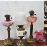 3 Oil Lamps – 1 with shamrock decorated bowl, 1 with figures in a garden, 1 with red bowl on a