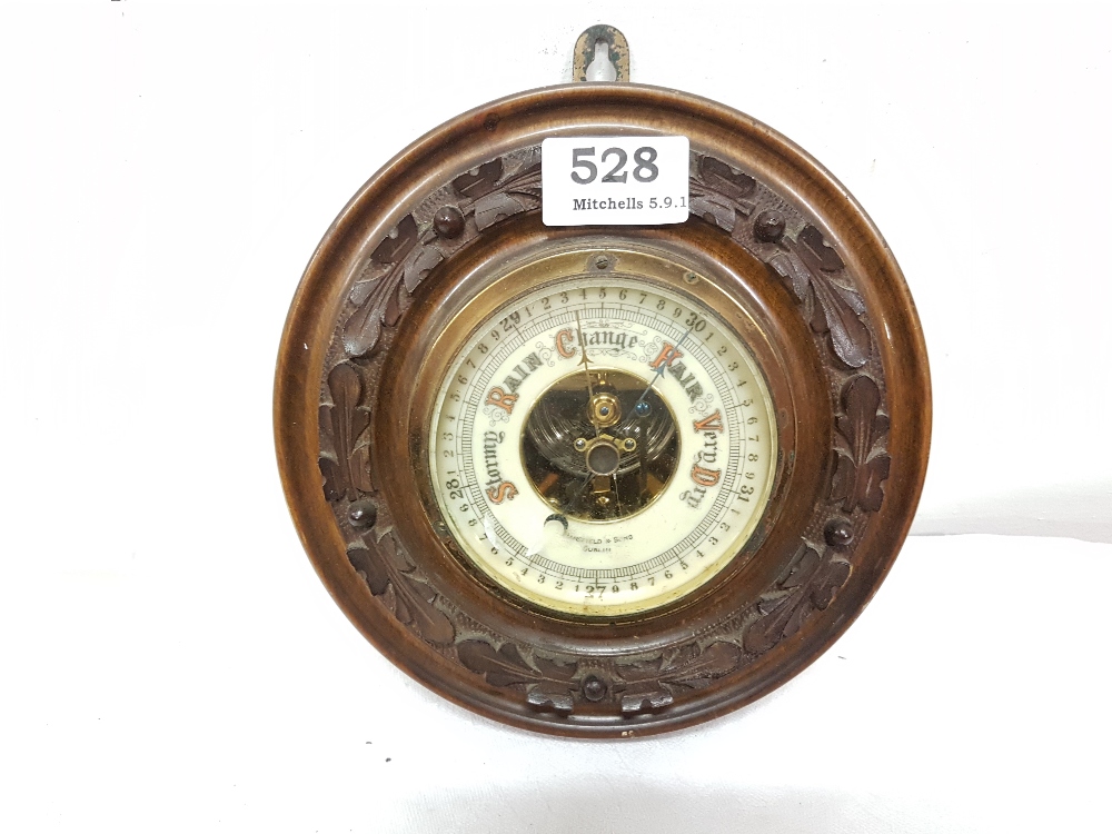 Circular wall barometer in a moulded oak frame, stamped “Mansfield & Sons, Dublin”, 8” dia