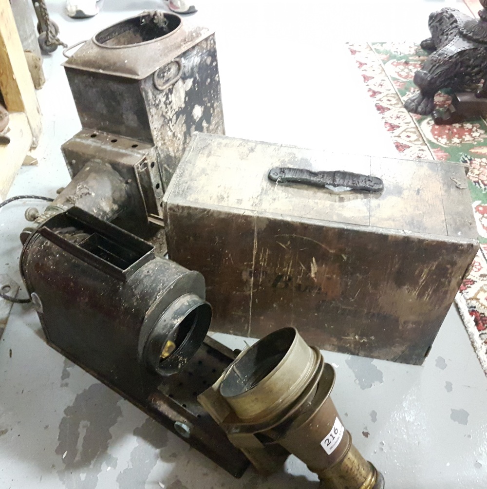 Old projector with brass framed lens, the original carrying case stamped E BARTON, CARLOW, also an