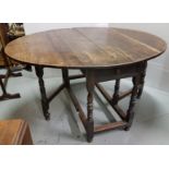 Early 20th C oak drop leaf dining/side table with oval shaped drop leaves, turned legs and