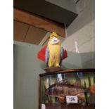 Taxidermy parrot mounted on a wooden plinth.