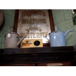 Metal watering can and an enamel watering can.