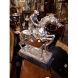 Silver plate model of a horse and jockey jumping.