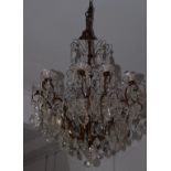 Lampadario quindici luci in metallo brunito con pendenti in cristallo. XX secolo. Mis. Alt. cm. 80