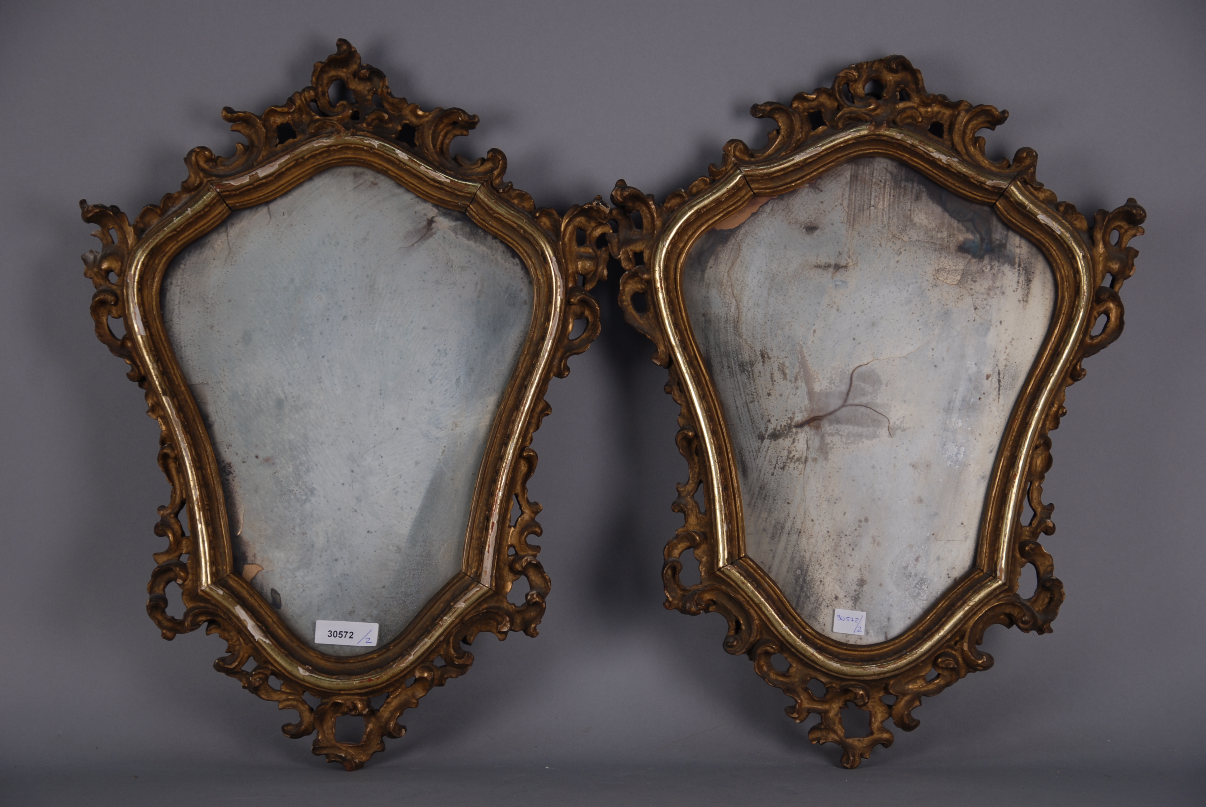 Due piccole specchiere con cornice in legno intagliato e dorato. XIX secolo. Difetti. Mis. Lung. cm.