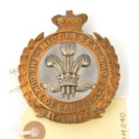 A Vic bi-metal puggaree badge of The Middlesex Regt, POW’s feathers in crowned title and wreath with