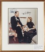 A full length coloured photograph signed “Ginger Rogers” and “Fred Astaire”, he seated on the arm of