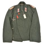 A Third Reich field grey short tunic or blouse, of an Artillery Leutnant, with silver bullion breast