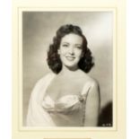 A waist length studio photographic portrait of Linda Darnell, mounted and framed, with inset